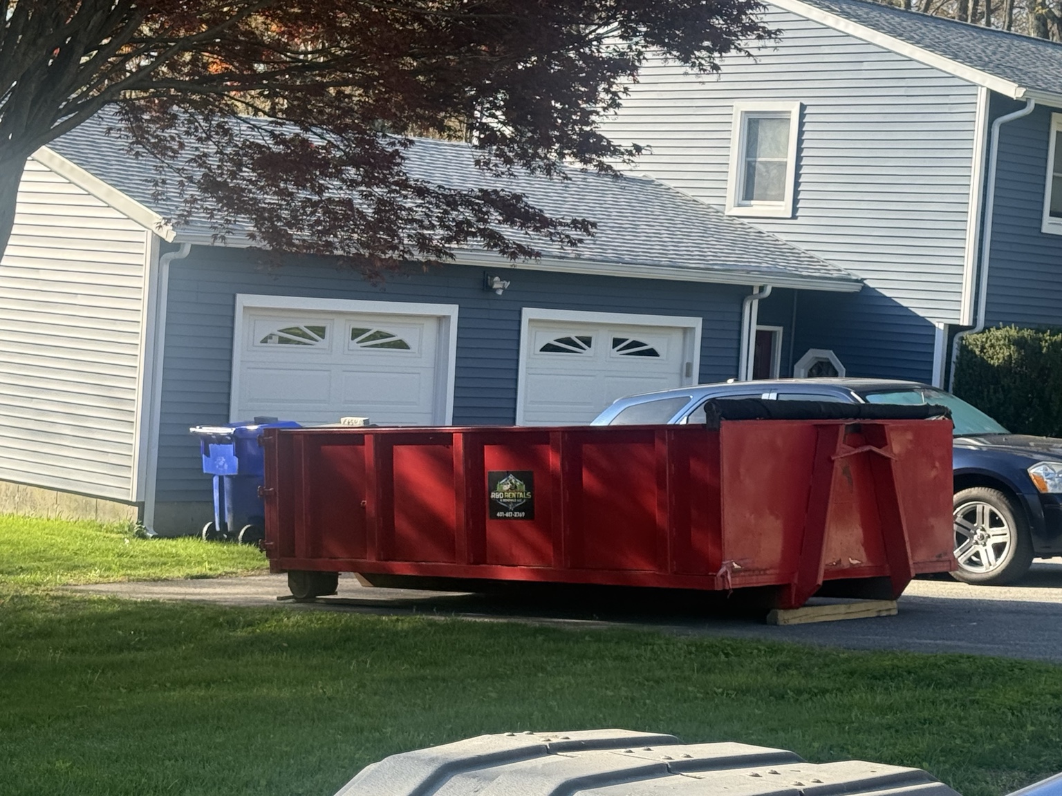 Red 10 yard R&D rental dumpster on a residential driveway